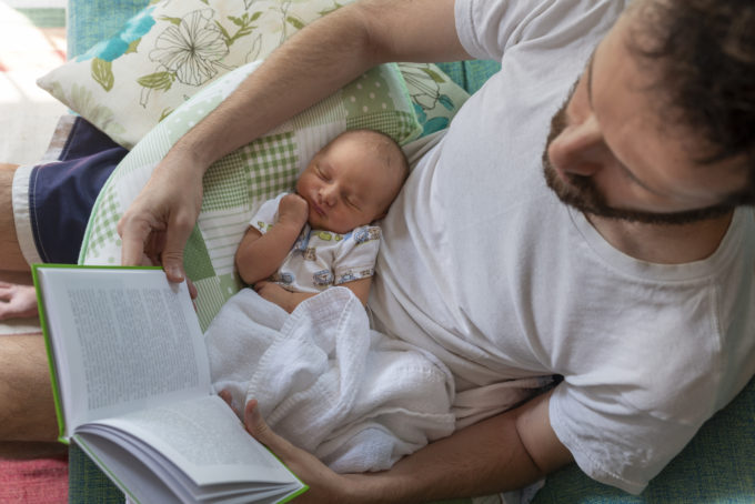 Father reading a book on the sofa with his baby daughter sleeping on his lap. Output, labor costs, profitability, and company survival are largely unchanged.