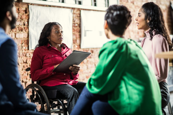 Businesswoman in wheelchair leading group discussion in creative office.