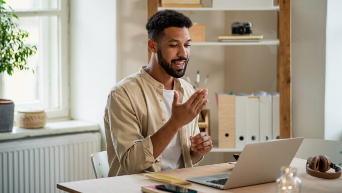 Disability Young man with laptop using sign language indoors in office video call concept