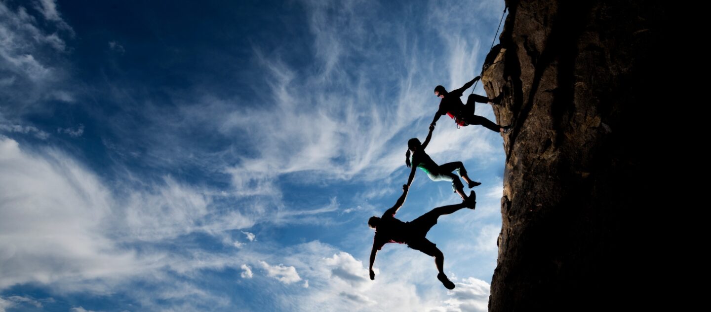People helping each other while climbing