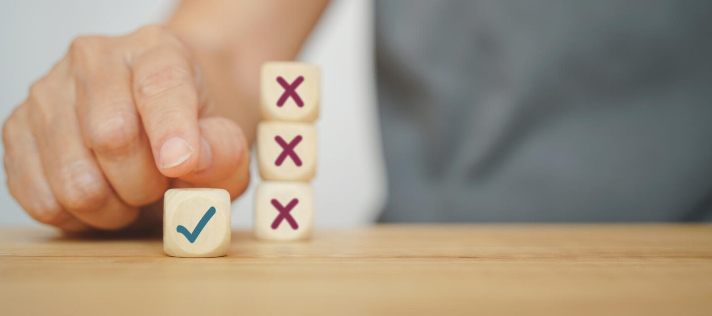 human hand choose correct sign on wood cube from experience for business, make a decision concept, in soft focus