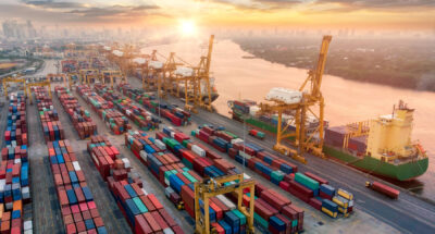 Aerial view and top view cargo plane flying above ship port in the export and import business and logistics international goods. Shipping cargo to harbor by crane