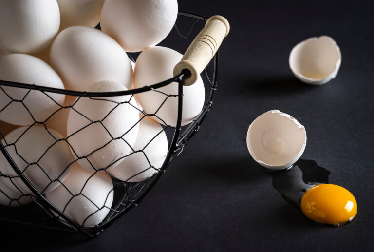 Cracked egg and basket full with chicken eggs