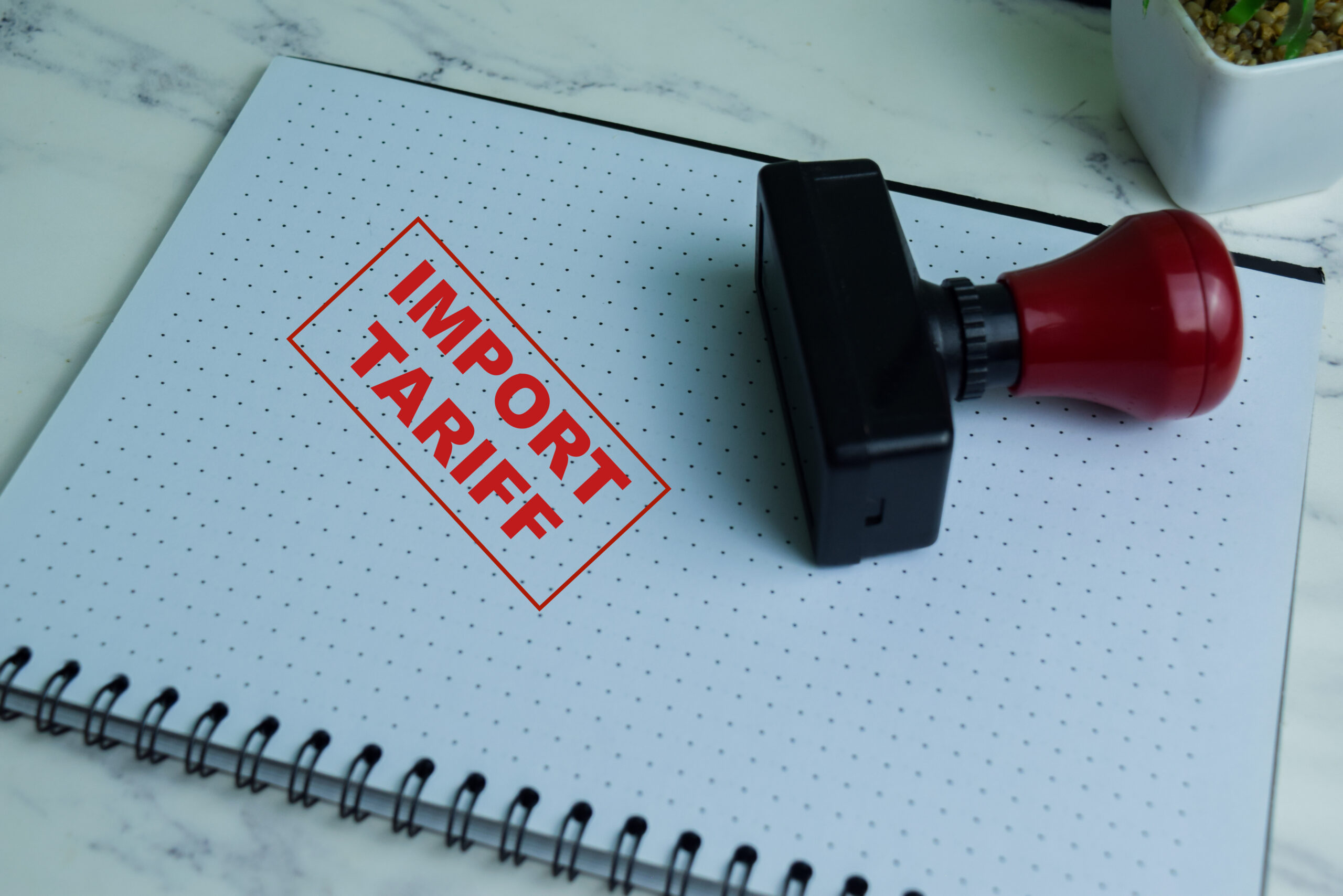 Red Handle Rubber Stamper and Import Tariff text isolated on wooden background - IMD Business School