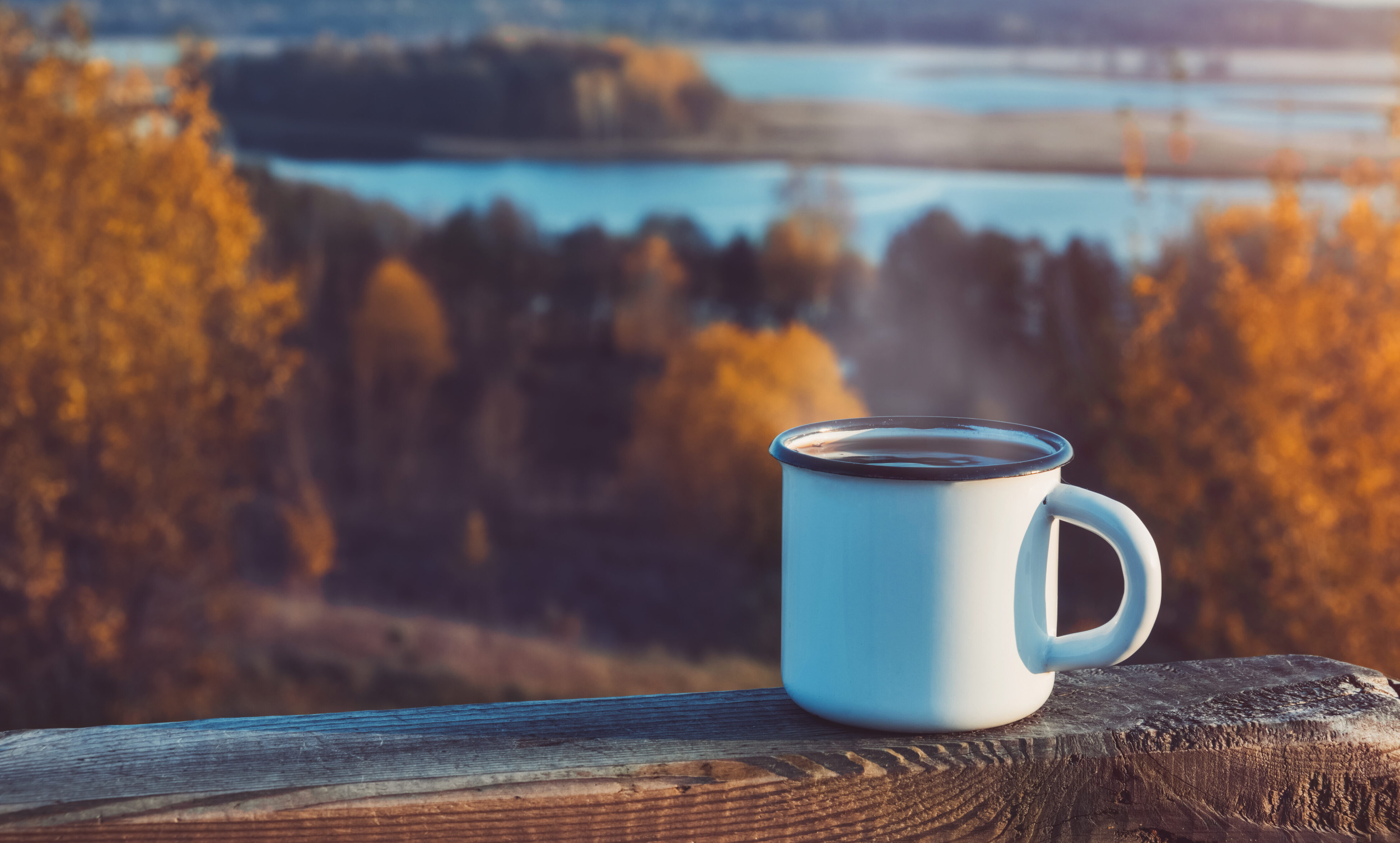 Enameled cup of coffee or tea on autumn landscape outdoors Coffee break