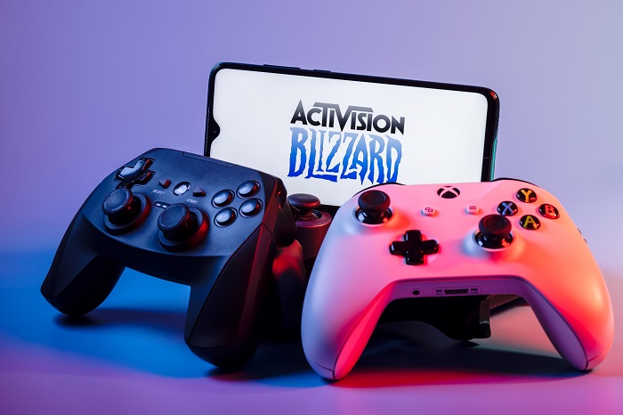 A smartphone with the Activision Blizzard logo on the screen on the pile of the gamepads. - IMD Business School