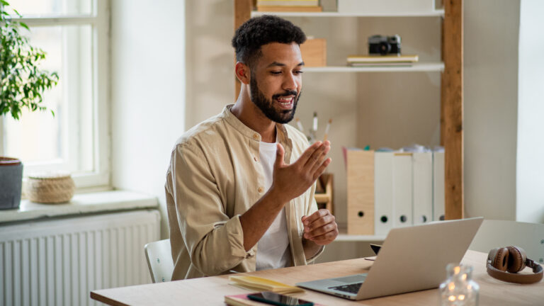Disability Young man with laptop using sign language indoors in office video call concept