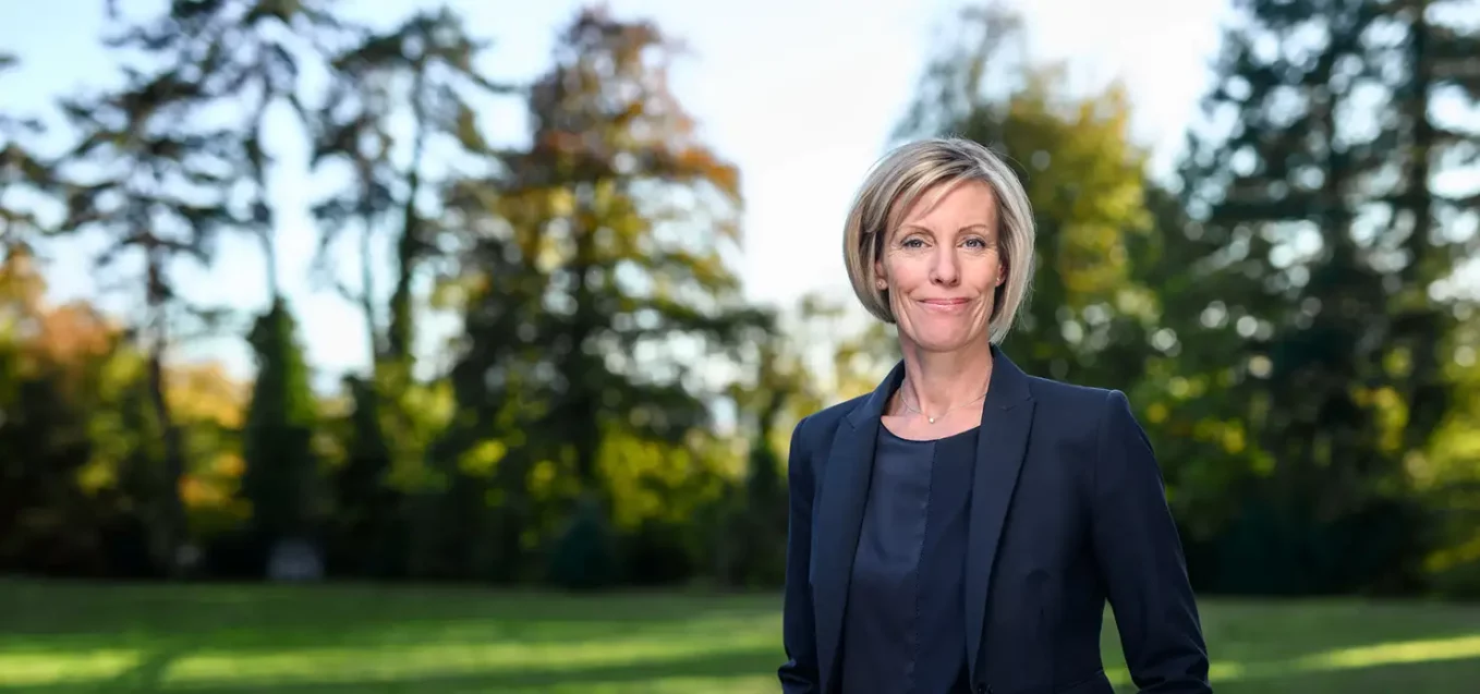 Anna Dunand, Chief Business Development Officer, standing on the IMD Lausanne campus gardens - IMD Business School