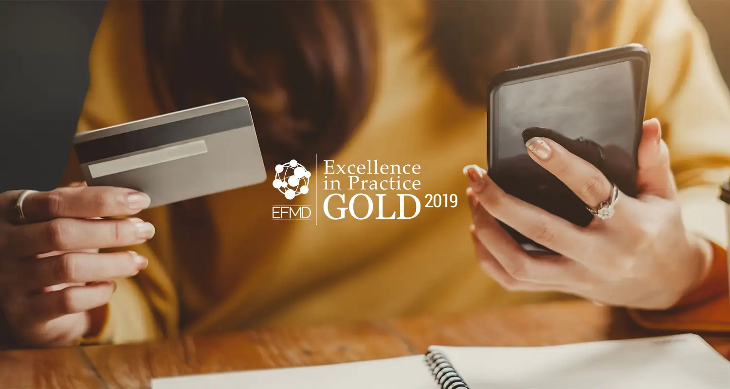 Woman holding a credit card and a phone + EFMD Gold award 2019 logo