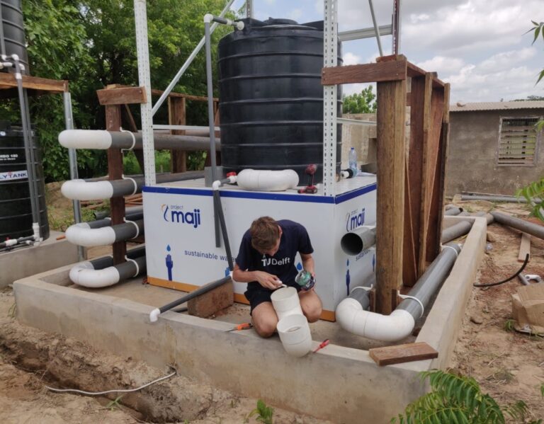 Jaspar Schakel laying some pipework inside a polytank to convert it into a sedimentation tank during a trip to Ghana in 2022 to work on a prototype. - IMD Business School