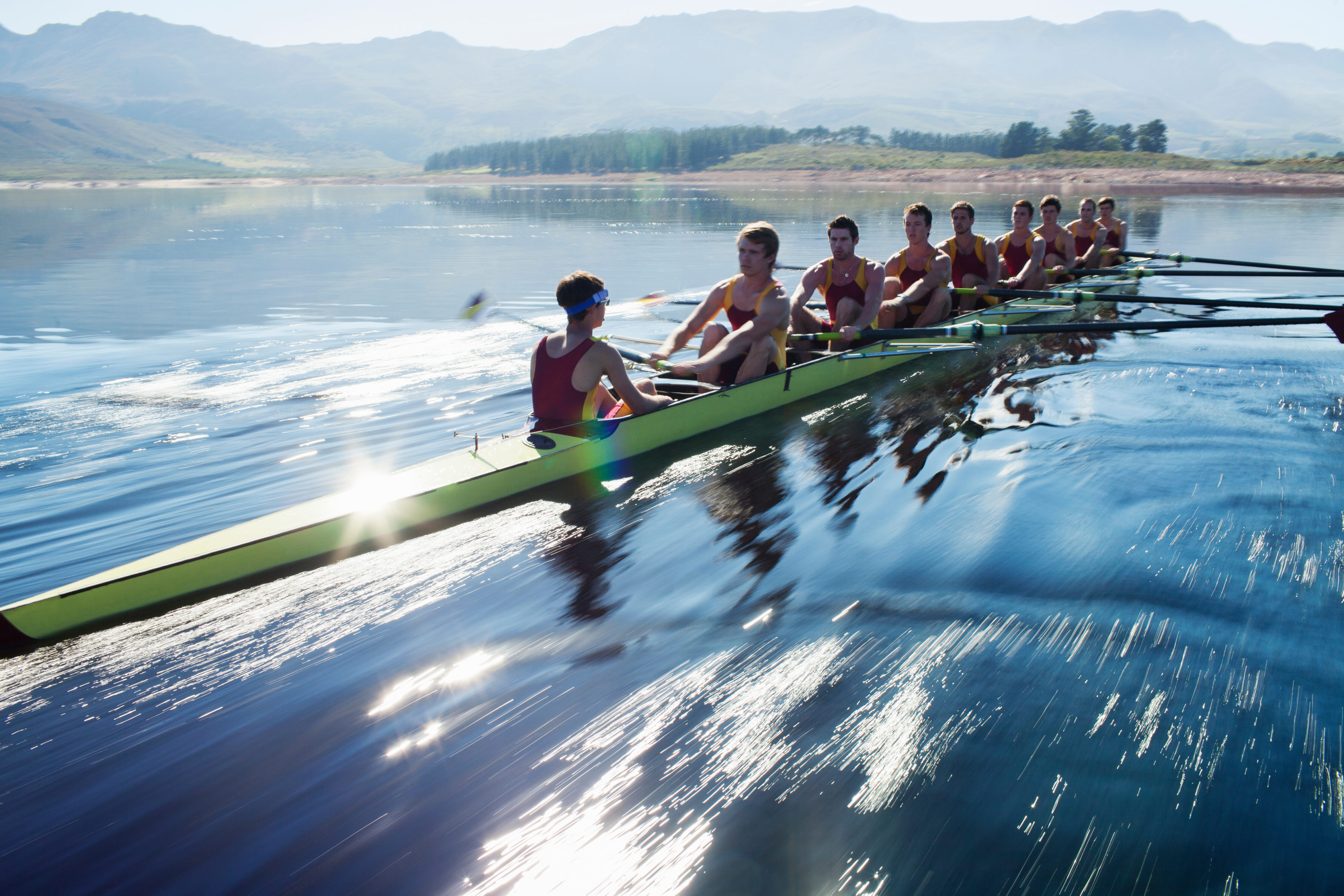 Rowing team rowing scull on lake rowing