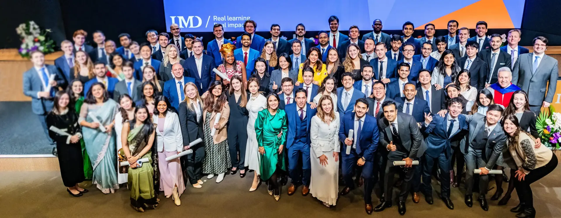 IMD 2023 MBA at their graduation on stage together cheering. - IMD Business School