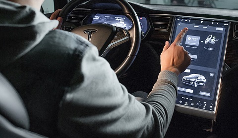 Interior or a Tesla vehicle, with someone using the touch screen - IMD Business School