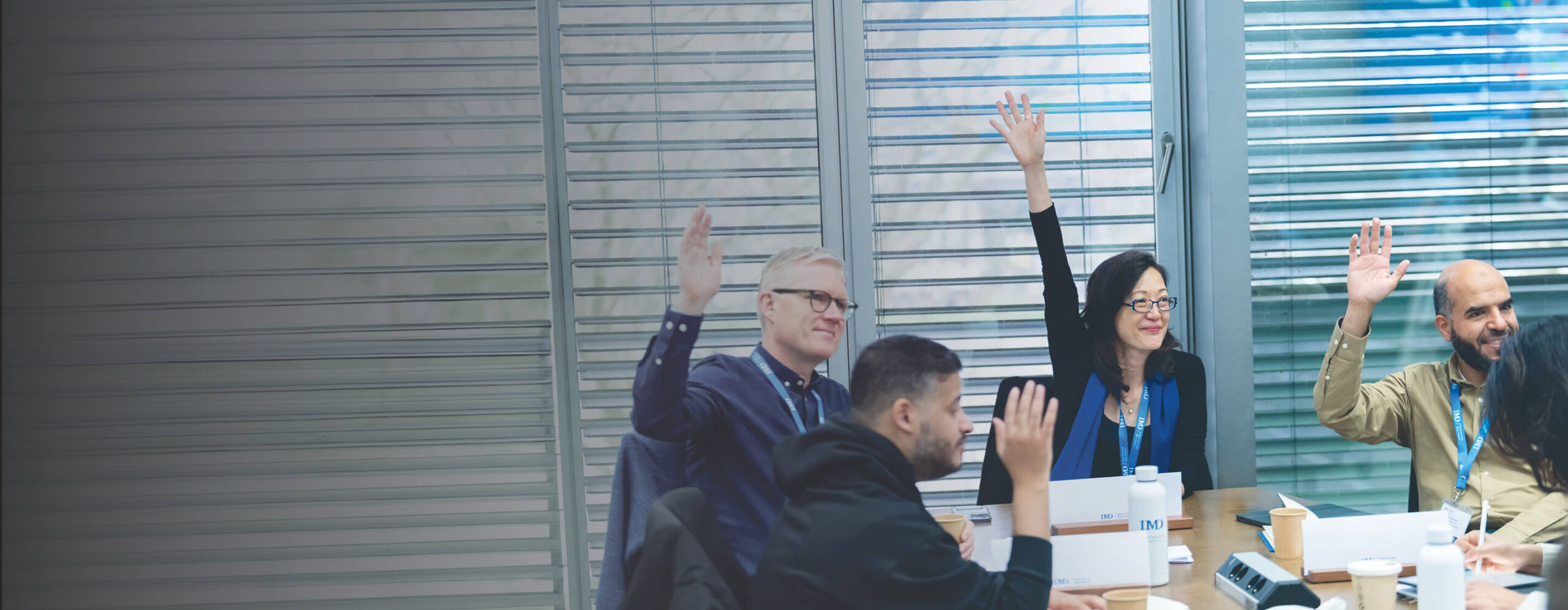 Open program participants raising their hands on class - IMD Business School