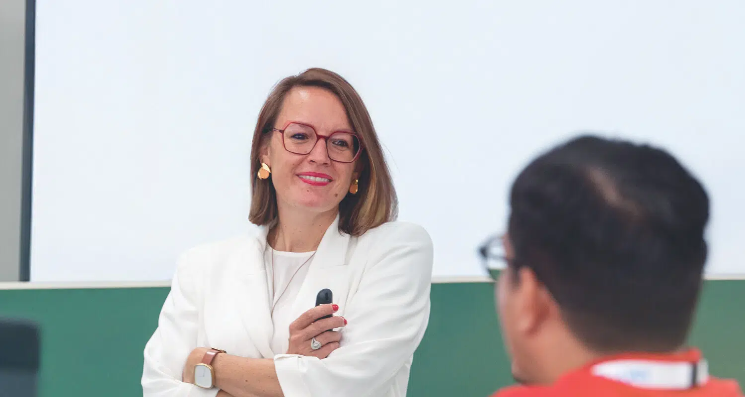 Professor Sophie Bacq at the front of a lecture listening to a program participant - IMD Business School