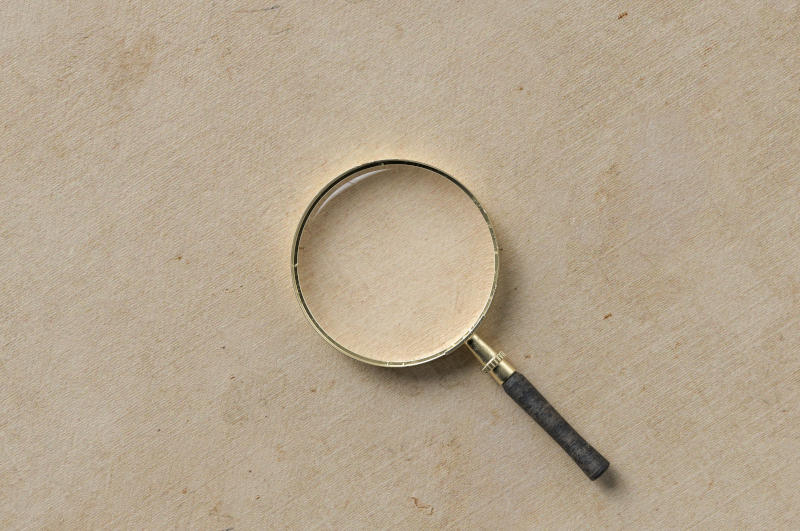 magnification glass on the left on empty paper background