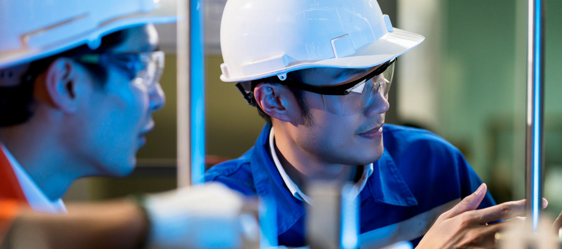 Male Asian engineer professional having a discussion standing by the machine in the factory ,two asian coworker brainstorm explaining and solves the process curcuit mother board of the machine