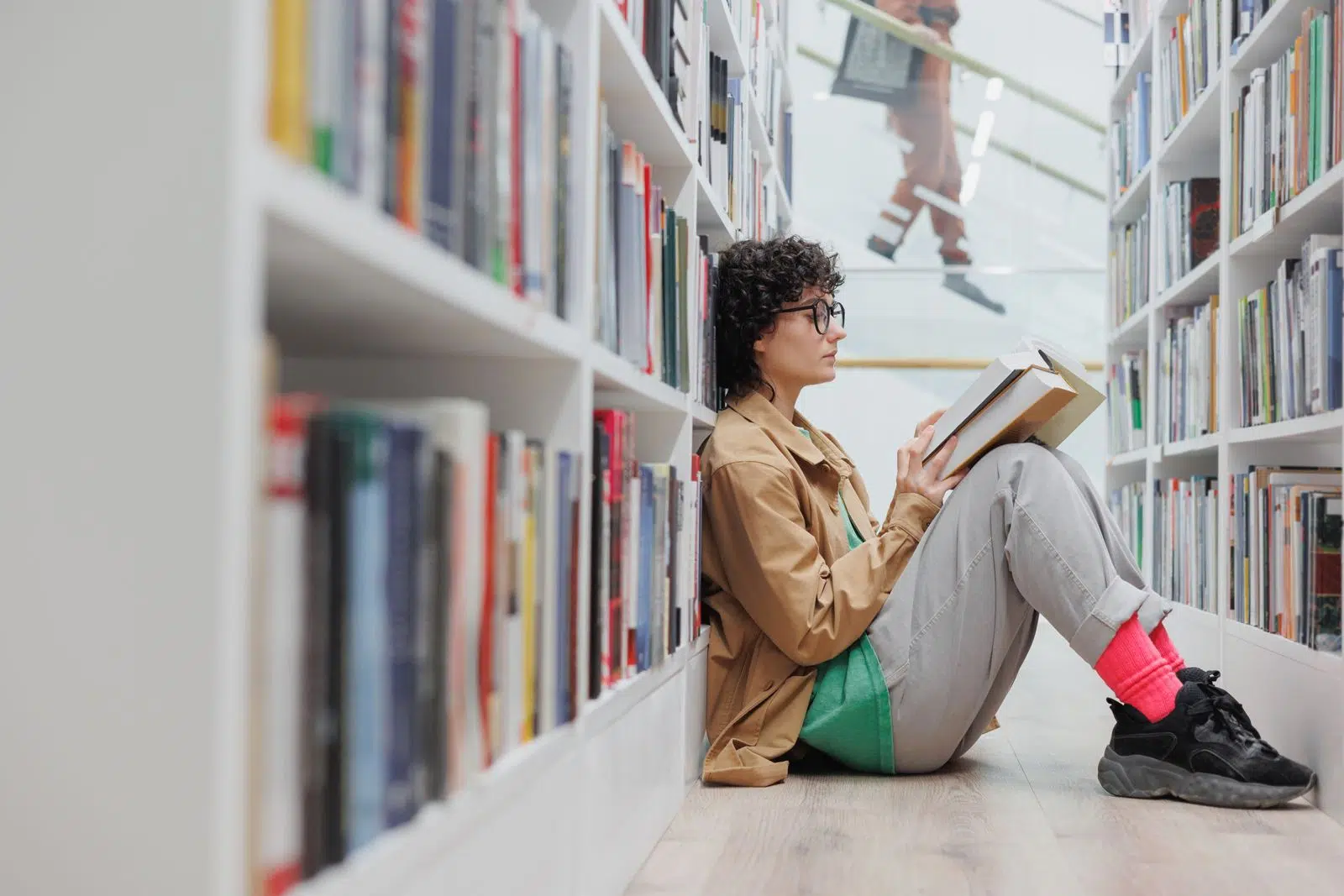 - IMD Business School Woman sitting on the floor reading a book in a library - IMD Business School