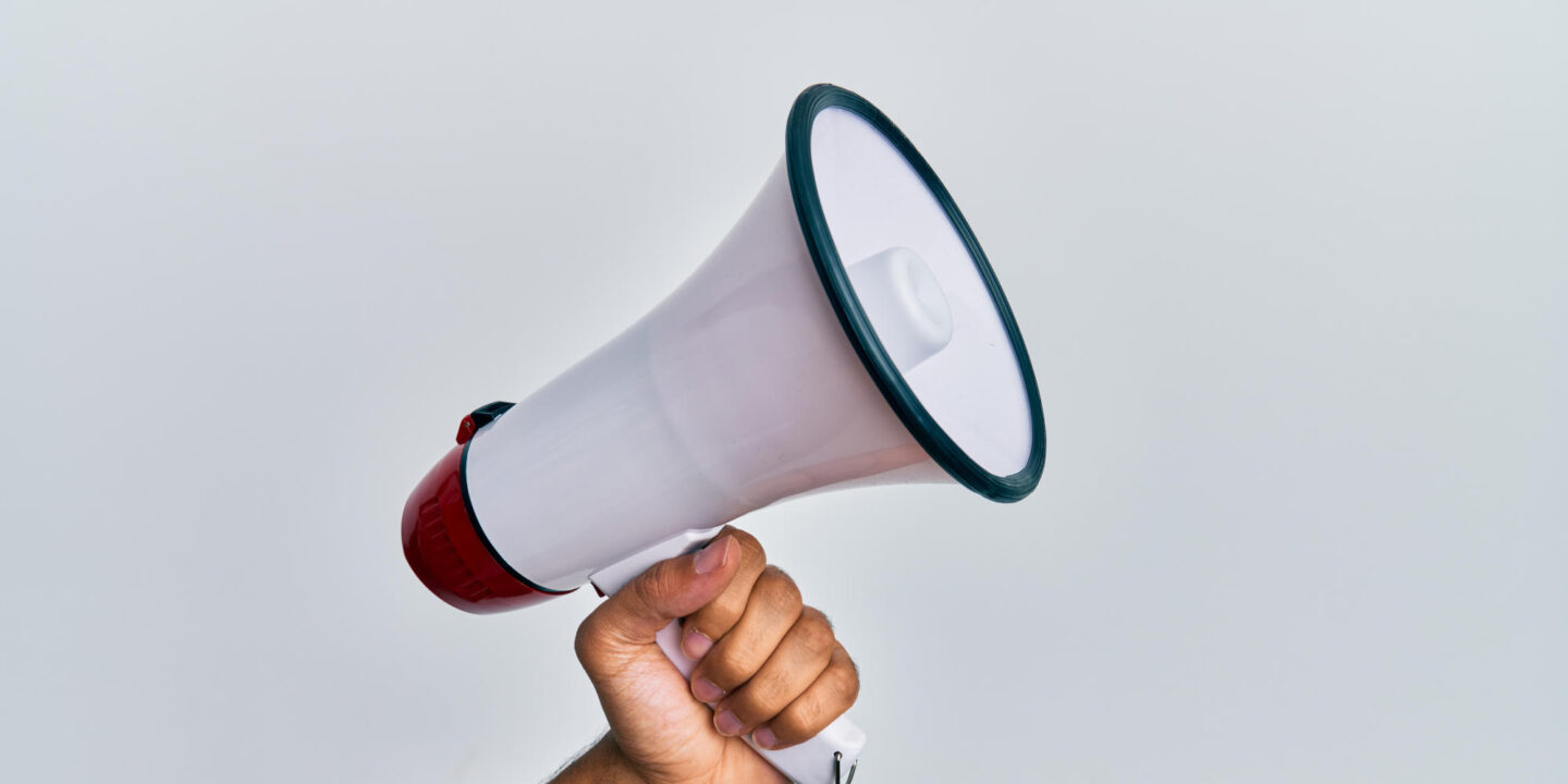 Hand of hispanic man holding megaphone over isolated white background