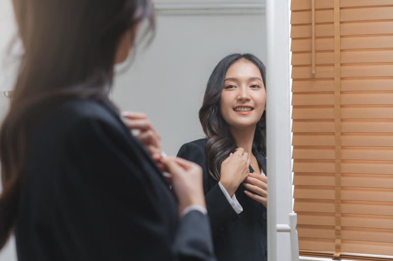 Confident, cheer up asian young woman standing in suit formal, getting dress for work looking at mirror at home before job interview of change career, recruitment employee or staff in company.