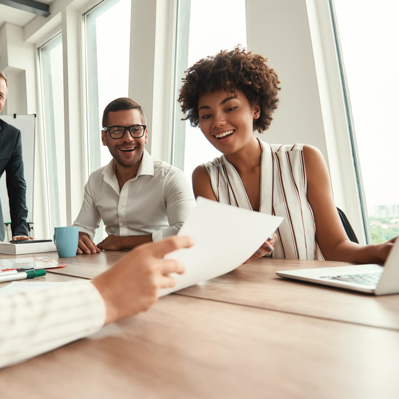 Great results! Group of young business people looking at documents and smiling while sitting at the office table. Brainstorming