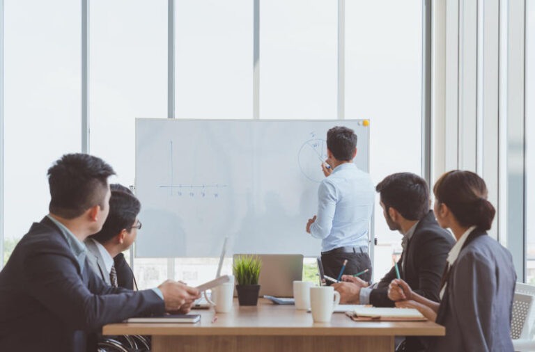 Businessman leader writing on the whiteboard present business marketing graph while meeting with colleagues in officeBusiness Team Meeting PresentationConference Planning Business Concept