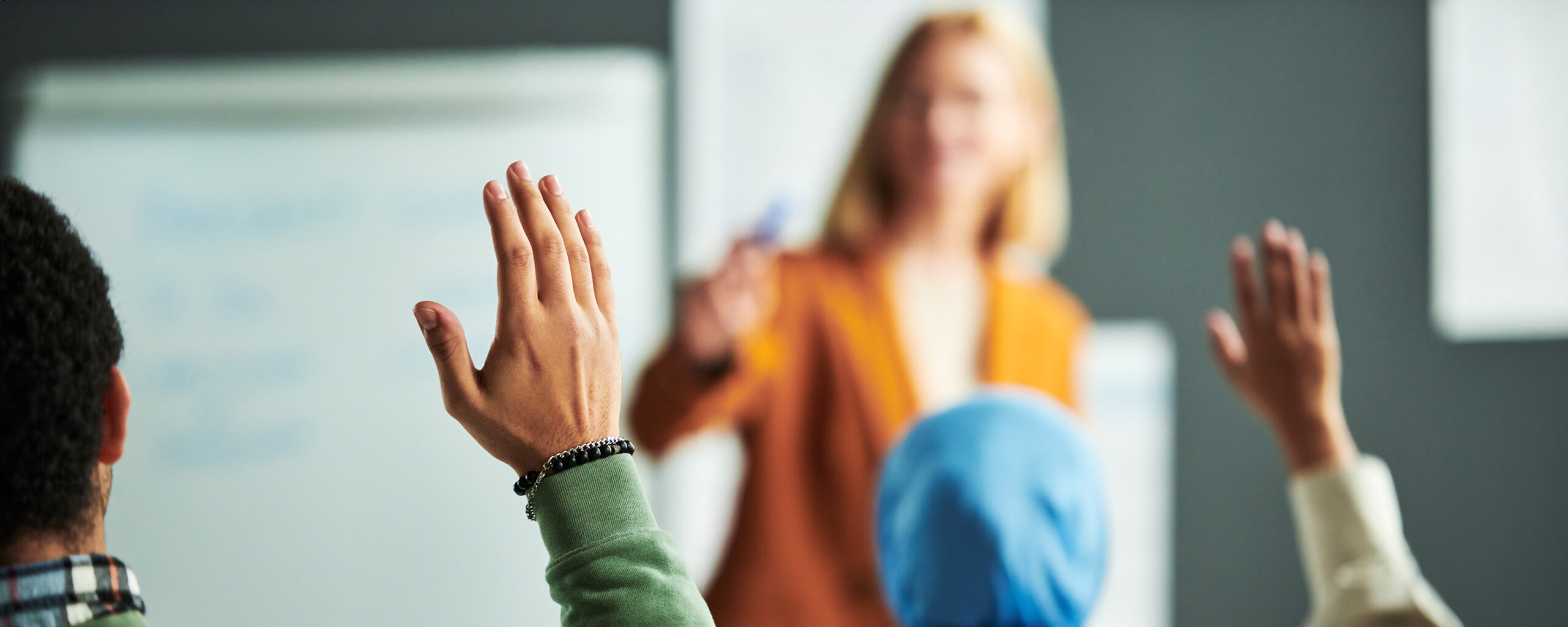 Raised hand of student working at seminar in front of speaker - IMD Business School