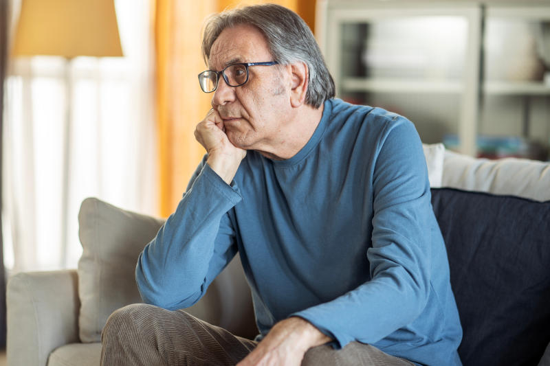 Old unhappy man sitting alone at home