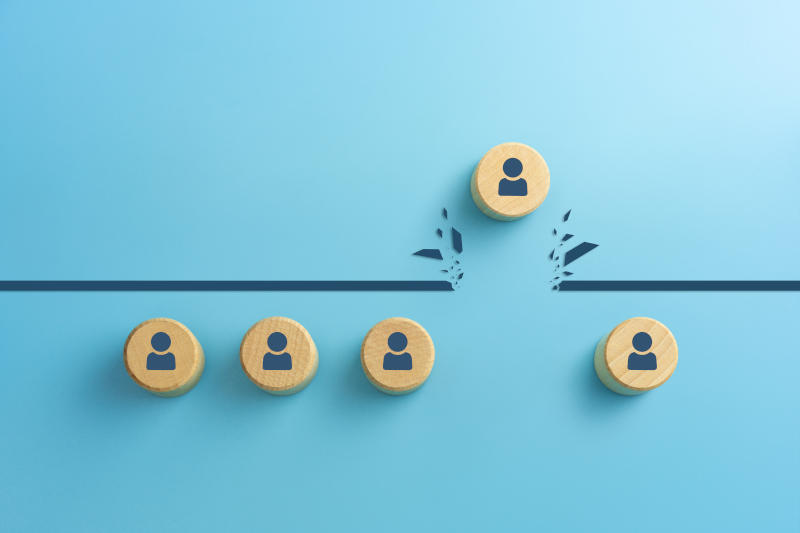 Wooden cubes with person icons breaking through obstacle on blue