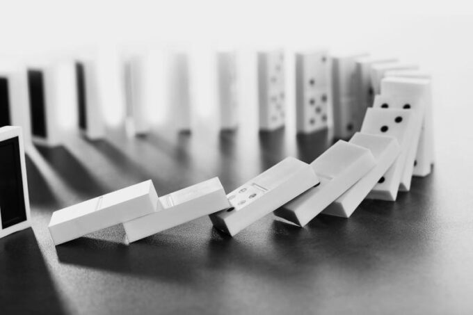 Dominoes falling on gray background
