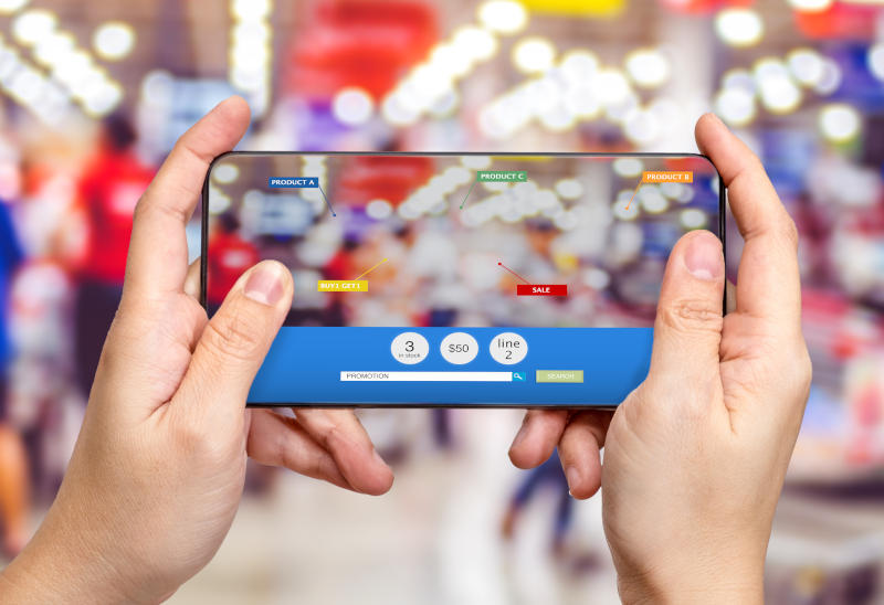 Hand hold mobile phone and using augmented reality AR app for see promotion sale in supermarket storeDigital lifestyle Technology concept