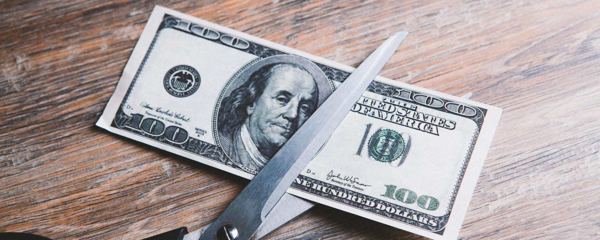 Scissors cut a dollar bill in half