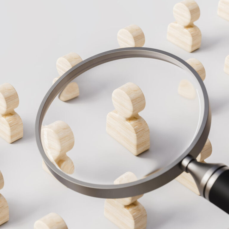 Magnifying glass searches for the best option in job profiles on white stage human resources