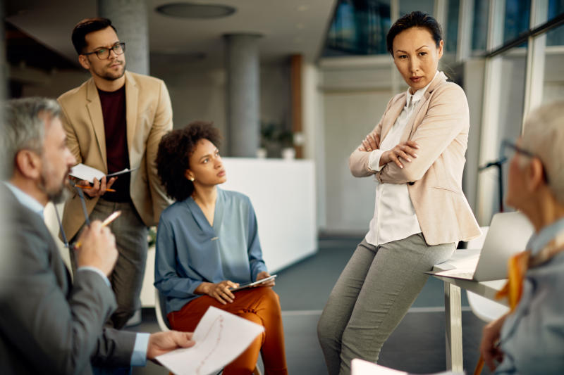 Confident Asian CEO communicating with her business team during a briefing in the office