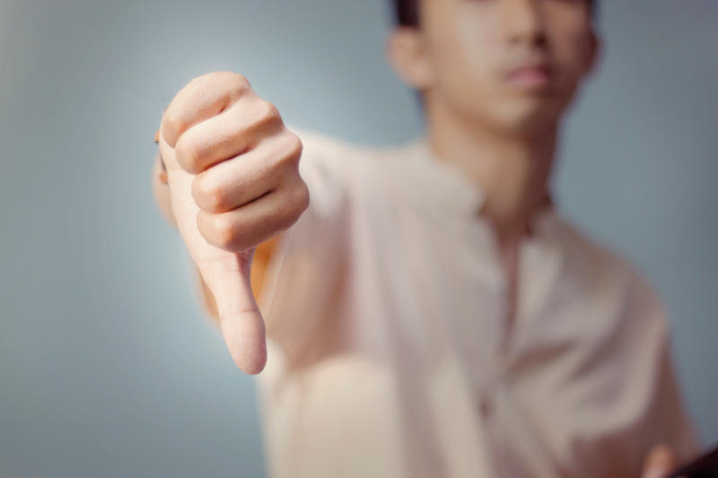 Close-up of hand showing thumbs-down gesture expressing disapproval rejection or dissatisfaction concept