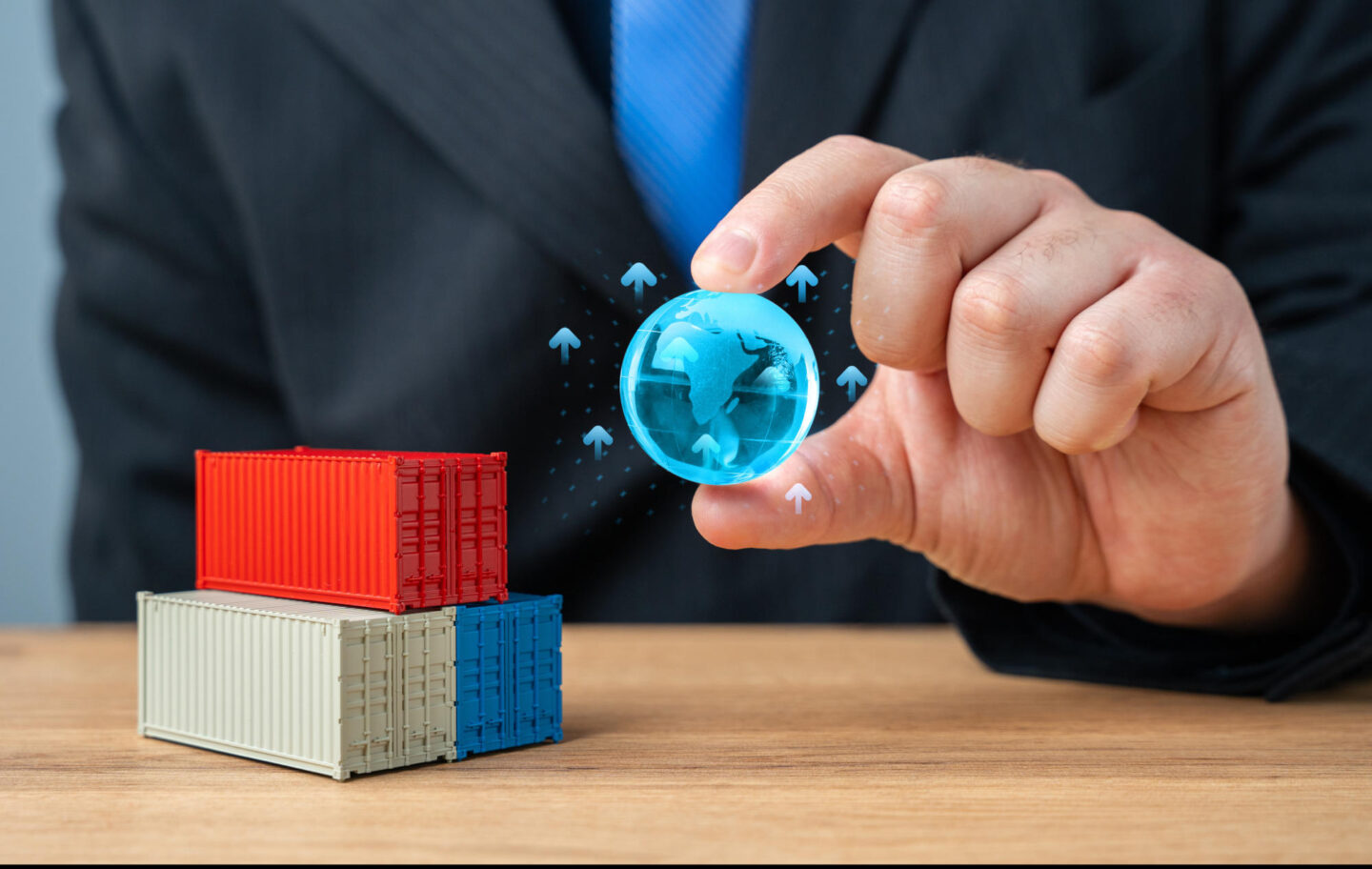 Businessman holding globe of planet Earth over stack of shipping containers World trade and economic processes Globalization Import export transportation of goods and logistics Production chains
