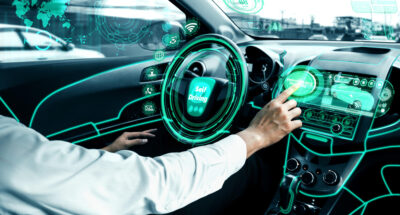 Self-driving autonomous car with relaxed young man sitting at driver seat is driving on busy highway road in the city Concept of machine learning artificial intelligence and augmented reality
