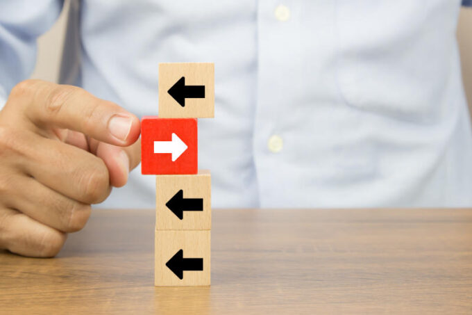 Businessman hand choose cube wooden toy blog with arrow head icons pointing to opposite directions for business change leader to growth and success concepts