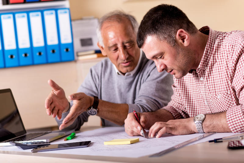 Senior and young architect working together on a project in the office senior architect mentoring young colleague