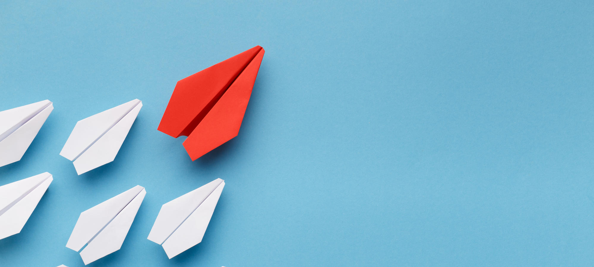 Blue paper boat leading among white ships