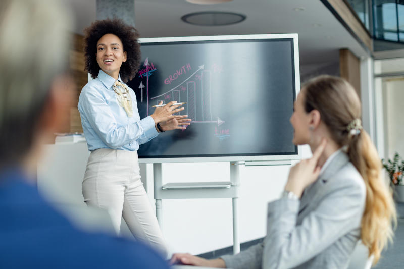 Black female entrepreneur presenting business growth chart during a meeting in the office Black female entrepreneur presenting business growth chart during a meeting in the office