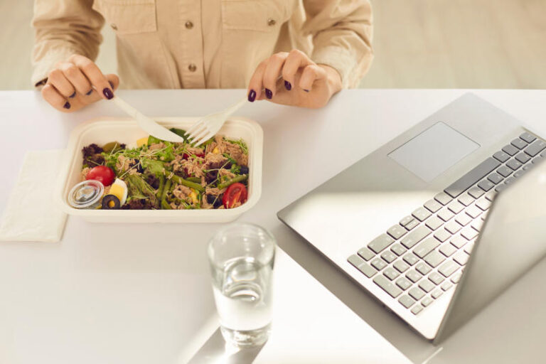 Busy student having healthy takeaway lunch from meal container during working day