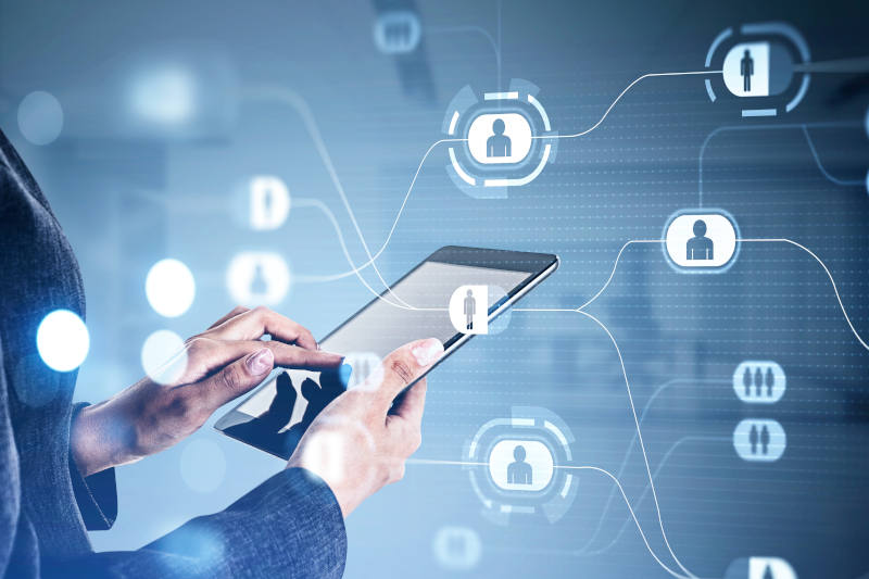 Businesswoman wearing formal suit is typing message in social network using tablet device Hologram sketch of people icons on the foreground Communication via digital technology