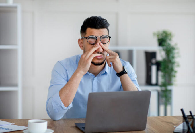 Millennial Arab businessman feeling fatigue from looking at laptop screen at modern office