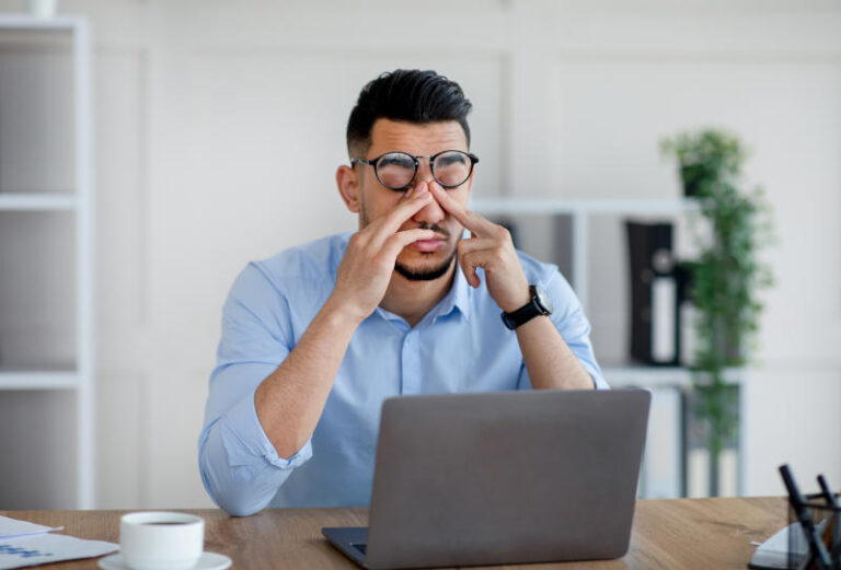 Millennial Arab businessman feeling fatigue from looking at laptop screen at modern office