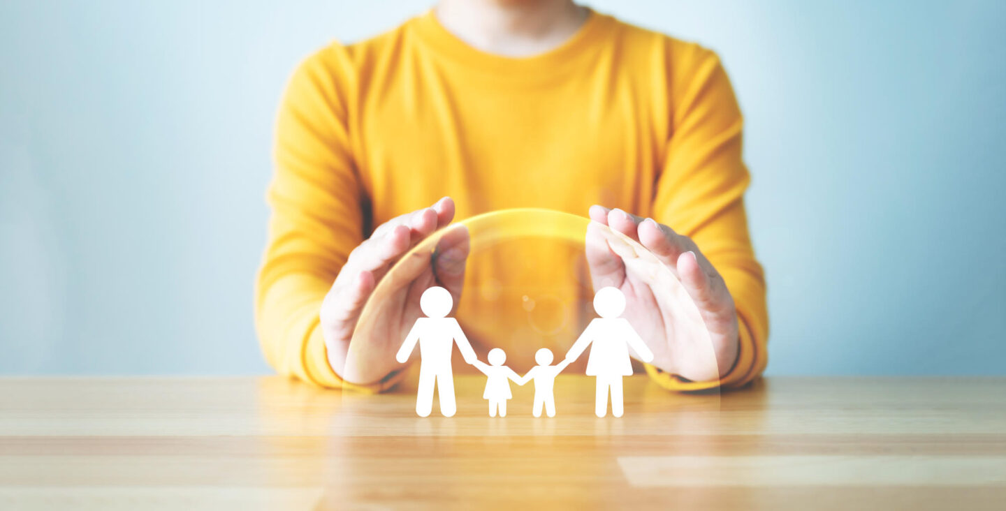 Hand protecting family on wood table Healthcare and life insurance concept
