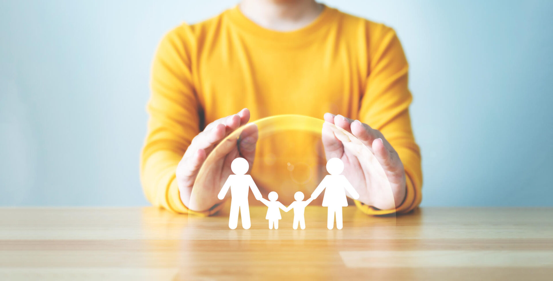 Hand protecting family on wood table Healthcare and life insurance concept