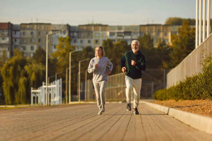 Senior man and woman running together during outdoor morning sports workout in city