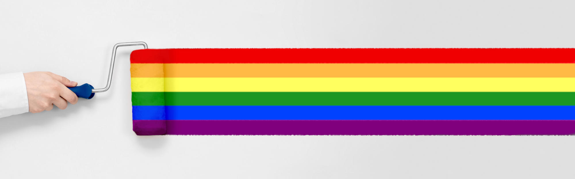 Hand holds a paint roller and paints rainbow-coloured line on white background