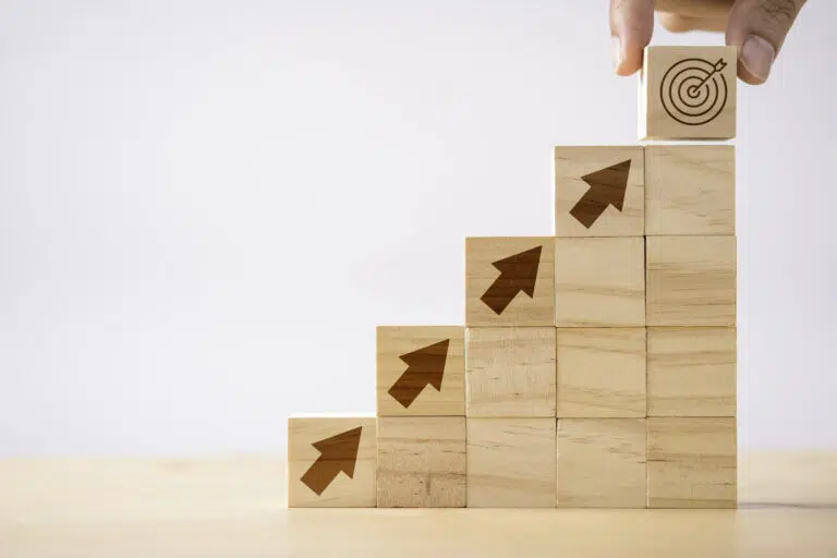 Hand putting print screen dart and target board wooden cube on up arrows Target of investment and business concept - IMD Business School